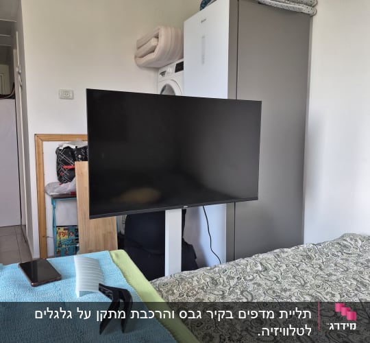 חדר עם טלוויזיה על מעמד, מכונת כביסה וארון